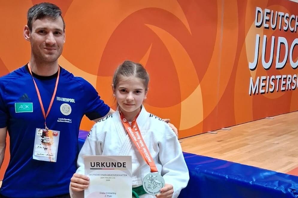 Alexander Lenk und Greta Emmerling Alexander Lenkt steht neben Greta Emmerling die eine Urkunde über den zweiten Platz sowie eine Medaille hochhält.