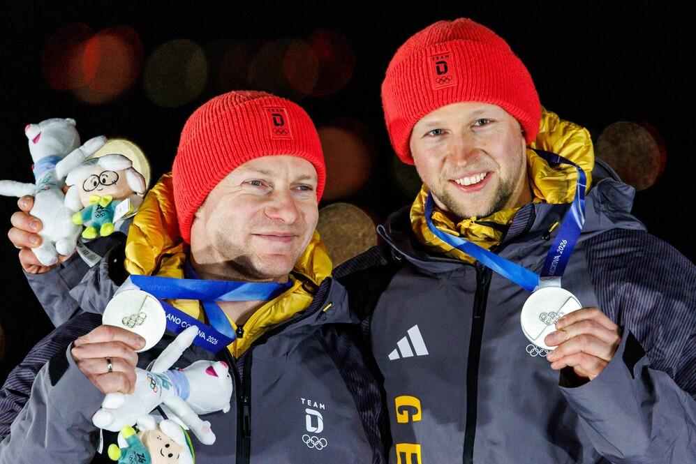 Silbermedaille für Alexander Schüller Francesco Friedrich und Alexander Schüller halten beide eine Silbermedaille von den Olmypischen Winterspielen 2026 hoch.
