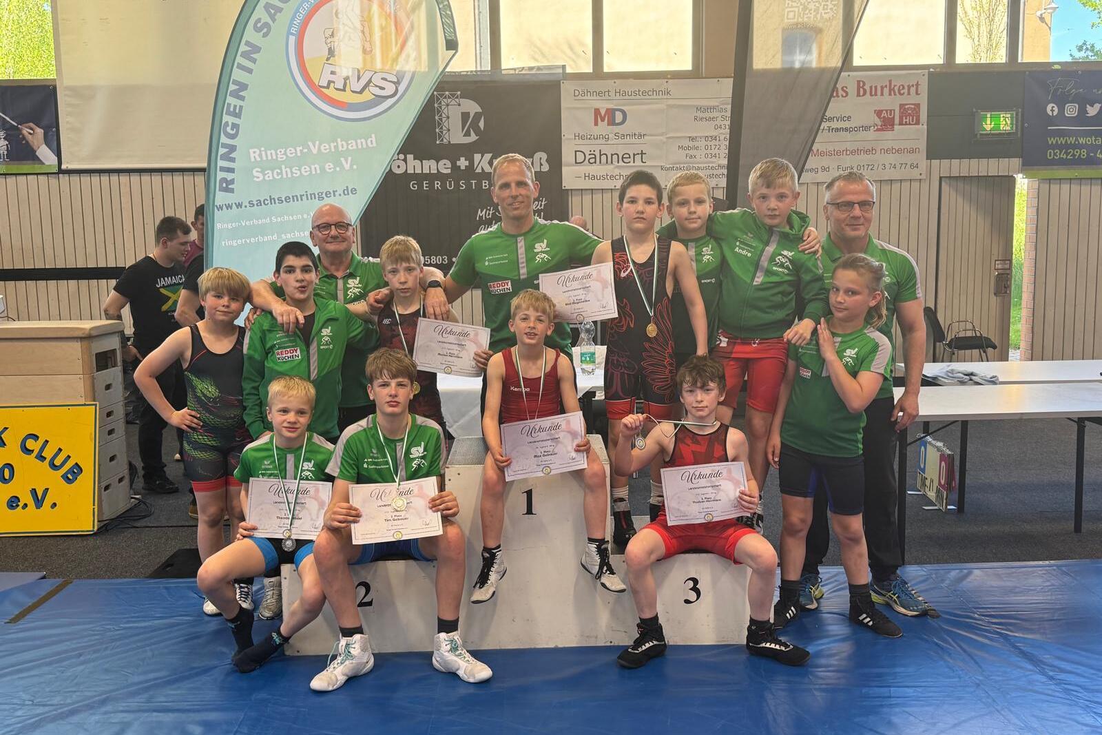 Teamfoto-Landesmeisterschaften-Taucha-2026 Die Sportler und Trainer aus der Abteilung Ringen posierern für ein Mannschaftsfoto mit Urkunden und Medaillen.
